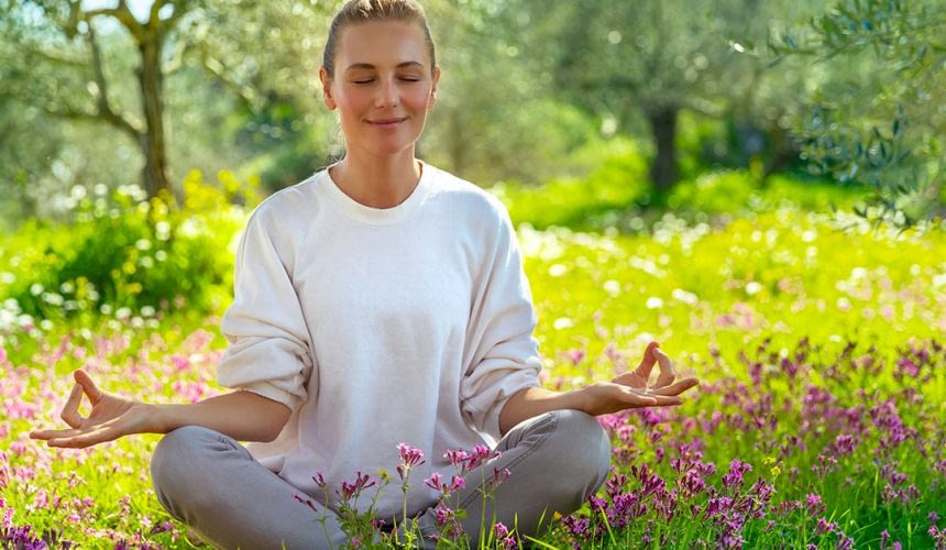 Beautiful calm girl with closed eyes meditating in the fresh blooming garden, unity with nature, zen balance, happy healthy lifestyle